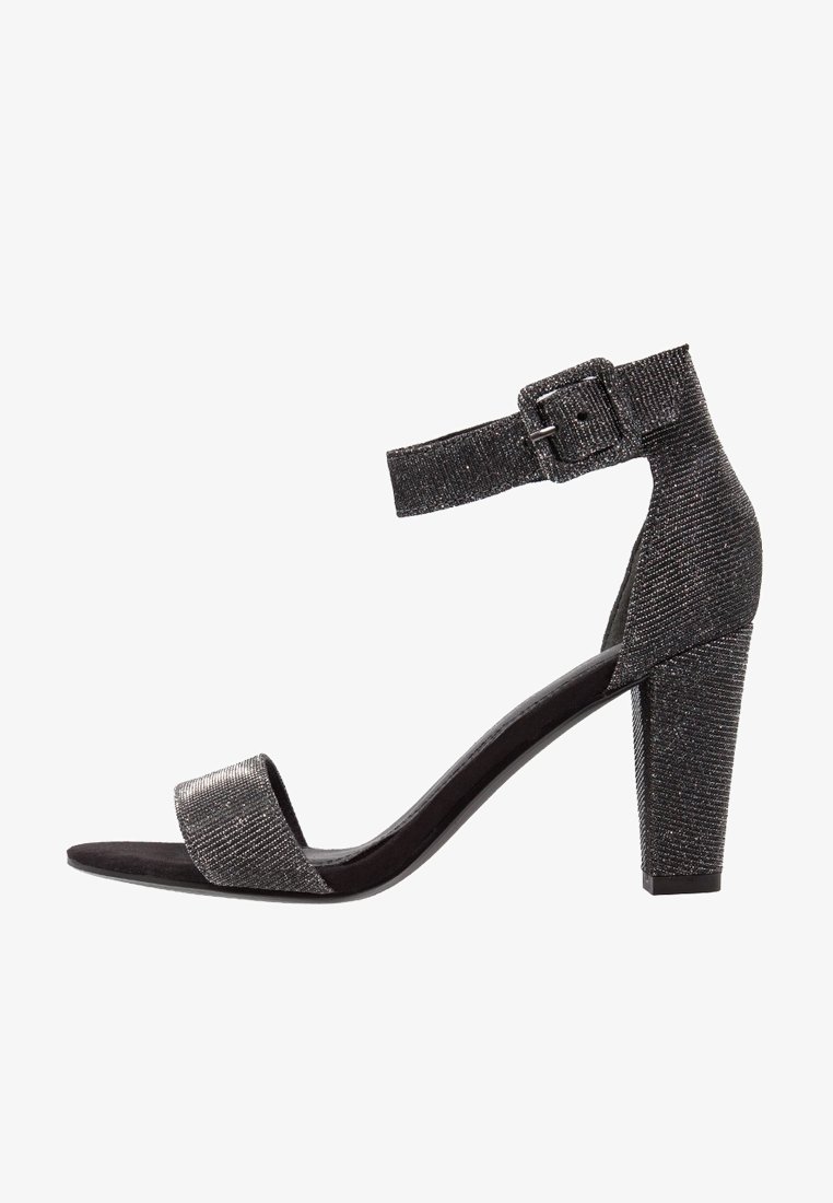 Sandale à talon haut noire en tissu texturé, avec bride à la cheville et fermeture à boucle, dotée d'un bout ouvert et d'un talon bloc.