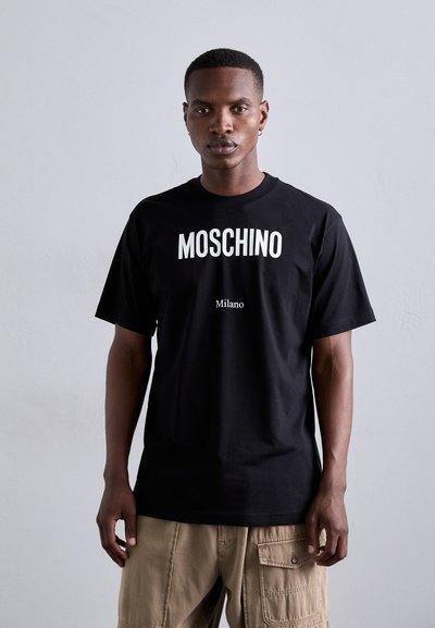 Sort bomulds t-shirt med fed hvid "MOSCHINO" tekst over en mindre "Milano" tryk. Rund hals og korte ærmer, med løs pasform.