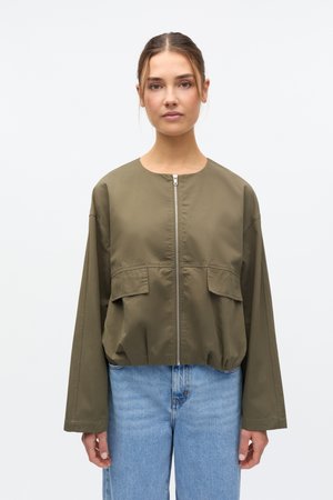 Veste courte vert olive avec col rond, fermeture éclair frontale et deux grandes poches plaquées. Présente des manches larges et une texture lisse et mate.