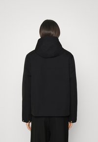 Black hooded jacket with a structured design, featuring a smooth texture, long sleeves, and snap-button accents on the cuffs.