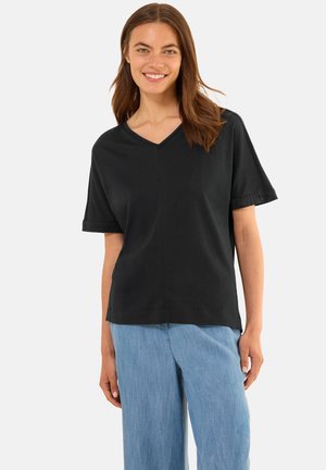 T-shirt noir à manches courtes et décolleté en V, fabriqué en matériau doux, avec une coupe décontractée et des détails de couture minimalistes, associé à un pantalon bleu clair.