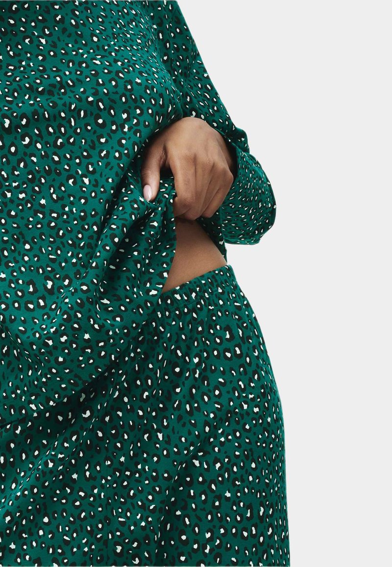 Sæt i grøn leopardprint til afslapning med blødt stof, lange ærmer og elastisk talje for komfort. Bemærkelsesværdige detaljer i sort og hvid.