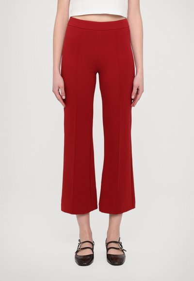 Red wide-leg trousers with a high waistband, featuring vertical seam details and a smooth texture, paired with dark, flat shoes.