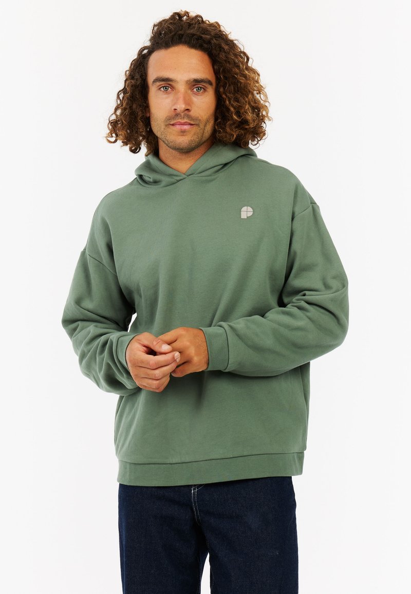 Groene hoodie van zachte stof, voorzien van een trekkoordkap, een logo op de voorkant en geribbelde manchetten. Gecombineerd met donkere jeans.
