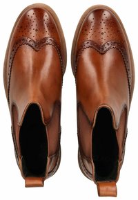 Braune Leder-Chelsea-Stiefel mit durchbrochenen Details, glatter Oberfläche und elastischen Seitenpaneelen, abgerundeter Zehenpartie und flacher Sohle.