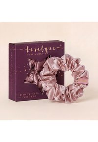 Roze luxe zijden scrunchie met kleine roze rhinestones naast een paarse stervormige doos met het label Lesilque Pure Moments.