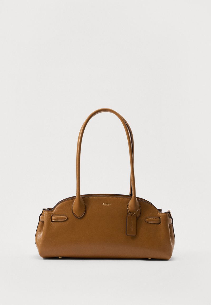 Καφέ δερμάτινη τσάντα με λεία υφή, στρογγυλό σχήμα, διπλές λαβές και διακοσμητική ετικέτα. Διαθέτει διακριτή ραφή και κομψό σχεδιασμό.