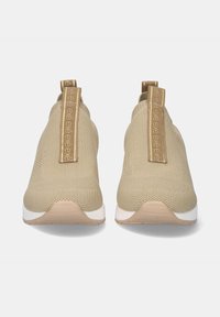 Zapatillas beige tipo slip-on con parte superior de malla texturizada, cuello de calcetín reforzado y tirador marrón con impresión de logo; suela blanca.