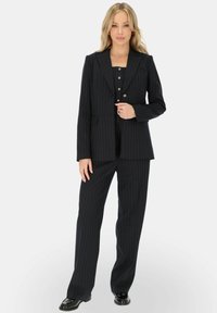 Czarny garnitur w prążki z dopasowaną marynarką i szerokimi spodniami. Gładka tekstura materiału, zorganizowany krój, z guzikami jako dodatkami na marynarce.