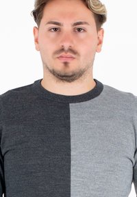 Sweter dzianinowy z okrągłym dekoltem, charakteryzujący się wzorem w blokach kolorystycznych w ciemnoszarym i jasnoszarym odcieniu. Gładka tekstura i dopasowany krój.