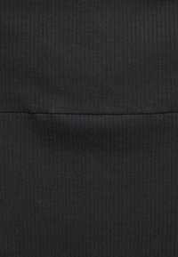 Černá žebrovaná látka s vertikálními pruhy a hladkým povrchem. Materiál se zdá být elastický a trvanlivý, ideální pro dobře padnoucí oblečení.