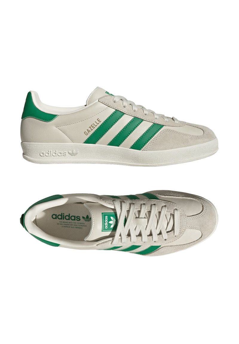 Des baskets Adidas Gazelle gris clair présentent des rayures et des accents verts. Le design met en avant un style athlétique classique avec un dessus texturé.