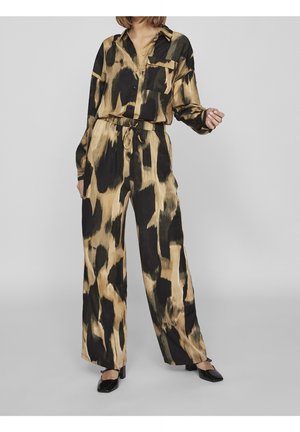 Ensemble de pyjama comprenant une chemise à boutons et un pantalon large dans un motif abstrait noir et beige, fabriqué en tissu lisse avec une coupe décontractée.