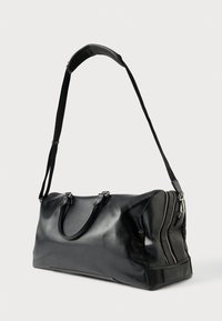 Fekete bőr utazótáska sima felülettel, dupla felső fogóval, állítható vállpánttal és egy oldalon ezüst cipzár részlettel.