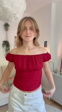 Rode off-the-shoulder top van textiel met een elastische halslijn en korte pofmouwen, gecombineerd met witte hoge taille broek.