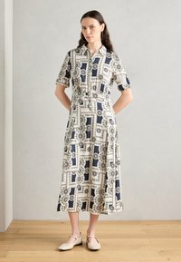 Shirt dress made from lightweight fabric, featuring a navy and white geometric pattern, short sleeves, and a button-up front.