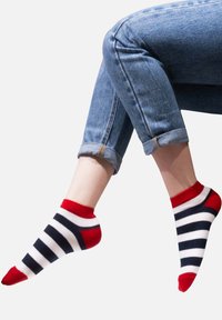 Paski skarpetki z czerwonymi mankietami i palcami, z poziomymi niebieskimi i białymi paskami. Miękki materiał, długość do kostek, noszone z podwiniętymi dżinsami.