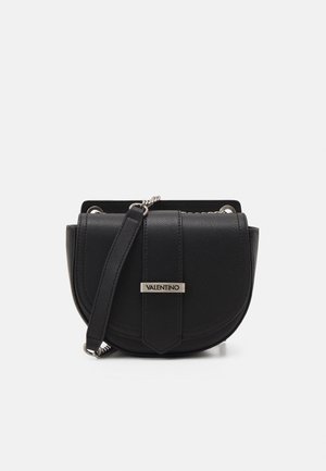 Czarna skórzana torba na ramię Valentino w stylu saddle z przednią klapą, srebrnym łańcuszkiem i skórzanym paskiem na ramię oraz metalową tabliczką z logo na zapięciu klapy.