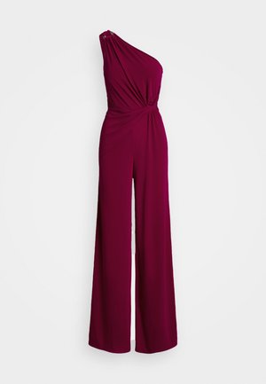 Eén-schouder jumpsuit in diep bordeauxrood, met een geknoopte taille, wijde benen en een gladde, vloeiende stof met een lichte glans.