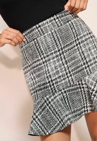 Fekete-fehér kockás szoknya, fodros végű. Texturált anyagból készült, rugalmas derékrésszel és sűrűn szőtt mintákkal rendelkezik.