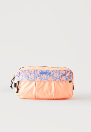 Bolsa rectangular color durazno con patrón geométrico azul en el bolsillo delantero y tiradores de cremallera negros sobre fondo gris claro.