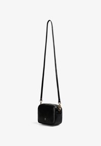 Bolso de cuero negro tipo bandolera con forma rectangular, textura suave y un detalle en dorado. Strap ajustable y cierre con cremallera.
