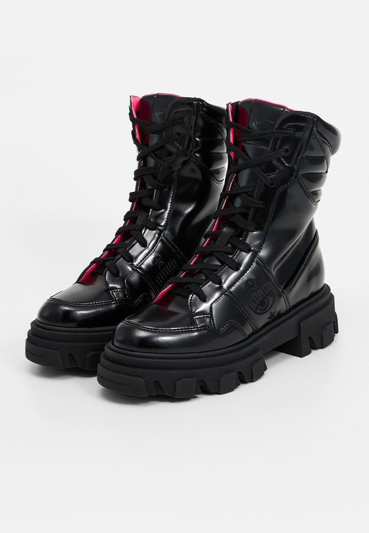 Czarne lakierowane botki za kostkę z różowym wyściółką, masywną czarną podeszwą i czarnymi sznurówkami. Posiadają logo oraz teksturowane akcenty po bokach.