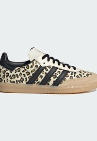 Buty sportowe w panterkę z białą skórzaną cholewką, czarnymi paskami i gumową podeszwą. Posiadają czarne sznurowadła i teksturowany czubek.