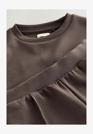 Ruskea kerroksellinen vaate, joka on pehmeä ja sileä tekstiili, jossa on pyöreä kaula-aukko ja rypytyksiä helmassa. Tunnistesignaali näkyy sisällä.