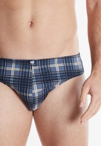 Herrenunterwäsche aus weichem Baumwollstoff in Marinekaros mit elastischem Bund und kontrastierenden gelben und hellblauen Linien in einem figurbetonten Design.