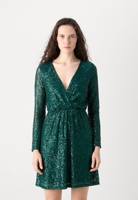 Abito verde con paillettes, maniche lunghe, scollatura a V profonda, vita cintrata e gonna svasata. La texture scintillante mette in evidenza dettagli intricati.