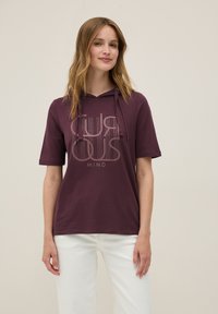 Sudadera burdeos de manga corta, con un estampado gráfico "MENTE CURIOSA" en tonos claros. Tejido suave y detalles con cordón.