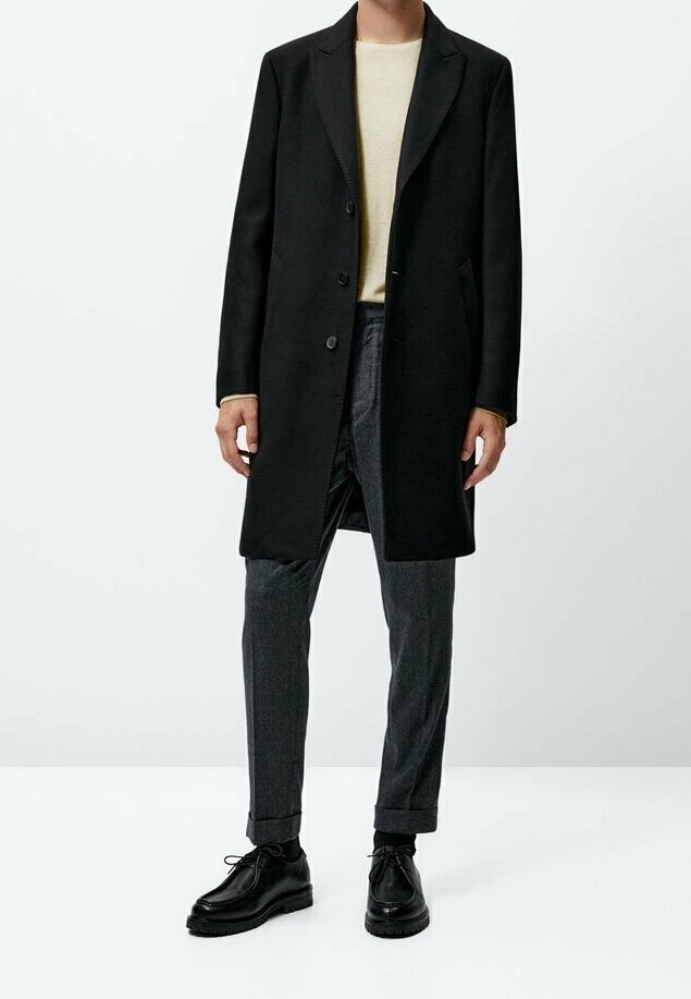 Schwarzer Wollmantel mit Kerbkragen, einreihiger Verschluss, kombiniert mit strukturierten grauen Hosen und schwarzen Lederschuhen.