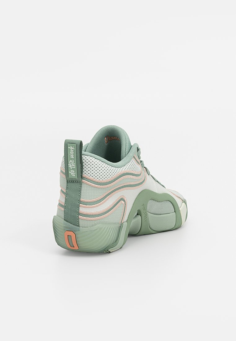 Scarpa sportiva verde e bianca con tomaia in rete, design curvo e accenti di pesco chiaro. Presenta un colletto imbottito e suola in gomma.