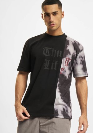 Svart og grå tie-dye t-skjorte med "Thug Life" trykk i svart. Korte ermer, løs passform og glatt bomullsstoff med distinkt fargeblokking.