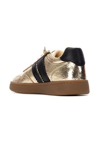 Zapatillas con un acabado dorado brillante, franjas laterales negras y una suela de goma. La parte superior texturizada añade brillo y un diseño moderno.