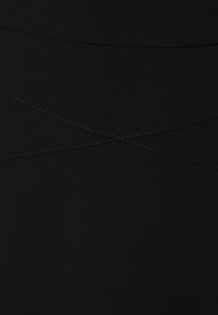 Schwarzer Stoff mit einer glatten Textur, der sich durch kontrastierende Nähte in einem Kreuzmuster über die Oberfläche auszeichnet. Einfaches, minimalistisches Design.