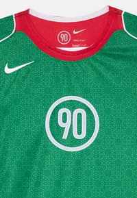 Žalias Nike Dri-FIT marškinėlis su raudonu apykaklės ir akcentų dizainu. Su tinklinio tekstūra, taškiniu raštu ir ryškiu baltu apskritimu su užrašu "90."