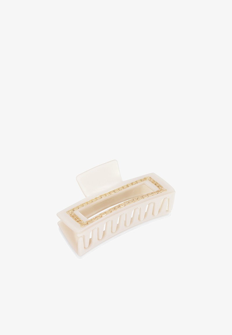 Fermaglio per capelli color crema in plastica, con un'apertura rettangolare e un'accensione della catena in tono dorato lungo il bordo. Artigli con presa testurizzata.