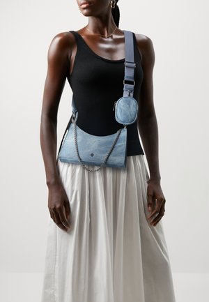 Blå denim crossbody taske med sølv kæde, justerbar rem og en lille aftagelig lomme. Glat tekstur, buet form og subtilt mønster.