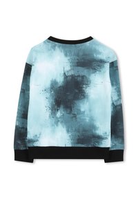 Haut à manches longues présentant un motif abstrait aquarelle bleu et noir, avec un col et des poignets côtelés noirs, fabriqué en tissu doux.