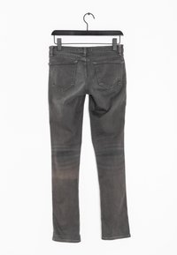 Jeans de denim gris con un diseño de pierna recta, cinco bolsillos y una textura desgastada. Colgado en la parte superior con una percha negra para su exhibición.