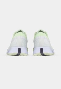 Πράσινα και λευκά αθλητικά παπούτσια με υφασμάτινο επάνω μέρος με υφή, που διαθέτουν εύκαμπτη σόλα και μωβ λεπτομέρεια στη φτέρνα.