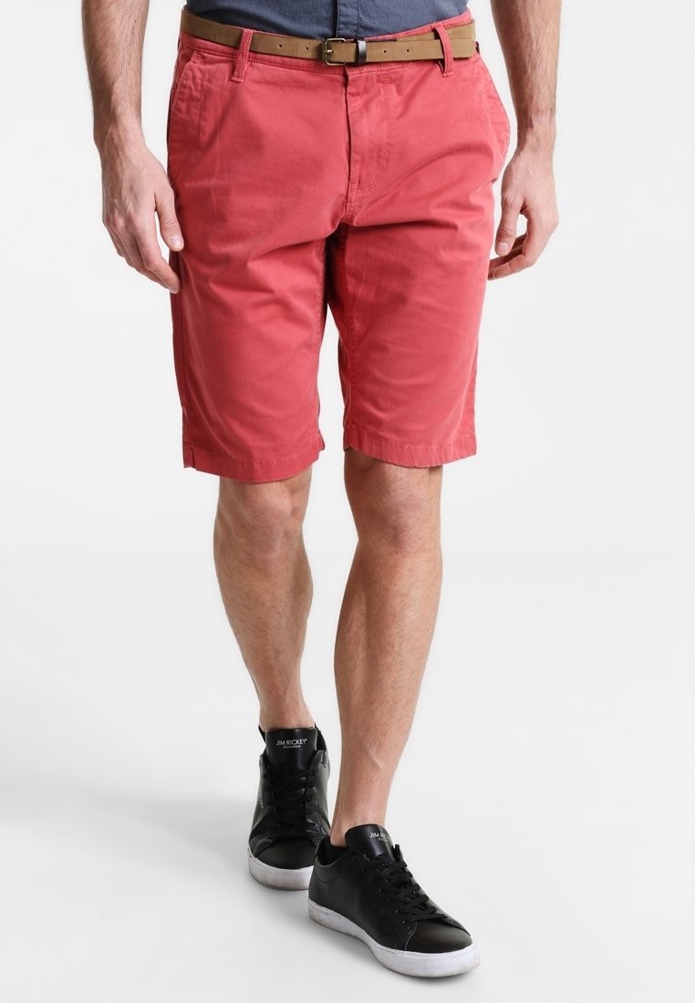 Shorts rouges en coton, avec un devant plat, des poches latérales et une taille avec passants de ceinture. Assortis avec des baskets noires.