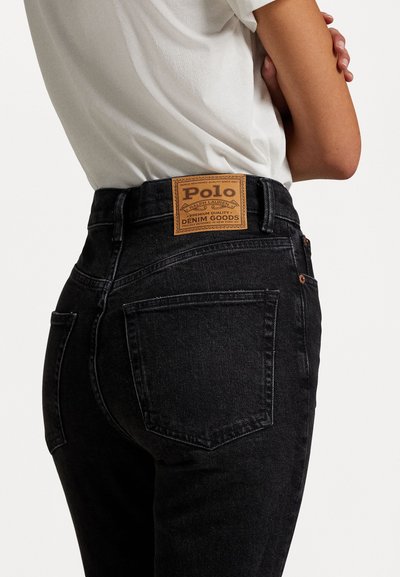 Zwarte denim jeans met een hoge taille. Heeft een leren label op de achterkant met de tekst "Polo." Standaard achterzakken en koperen details.