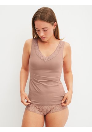 Donna che indossa un top mauve con bordi in pizzo e slip boyshort abbinati in pizzo, che guarda verso il basso, su sfondo bianco.