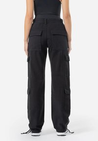 Black cargo pants with a loose fit, featuring multiple side pockets, a drawstring hem, and a durable cotton fabric.