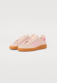 Lyserosa semskede sneakers med tre rosa striper, teksturert gummiyttersåle og rosa detaljer på hælen. Klassisk snøredesign.