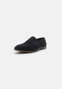 Loafer din suede navy cu vârf rotunjit, cusături decorative și talpă din cauciuc plat. Prezintă o bandă largă peste partea superioară.