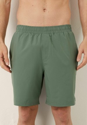 Grüne Schwimmshorts aus leichtem Stoff, mit elastischem Bund und seitlichen Taschen. Das Design ist einfach und hat keine sichtbaren Muster.